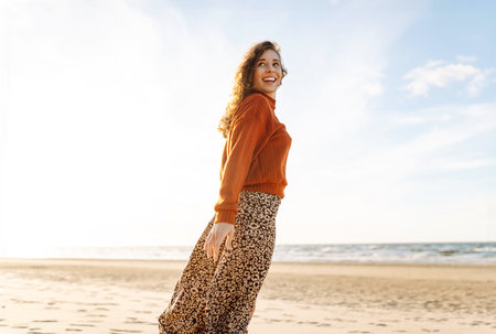 Portrait of a beautiful woman on the beach at sunset. Girl walks along the beach and enjoys weatherの写真素材