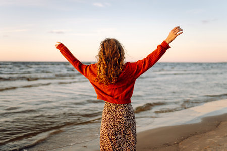 Stylish woman walks at sunset along beach of sea on at sunset. Travel, relax and lifestyle concept.の写真素材