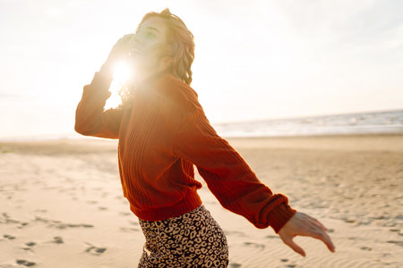 Portrait of a beautiful woman on the beach at sunset. Girl walks along the beach and enjoys weatherの写真素材