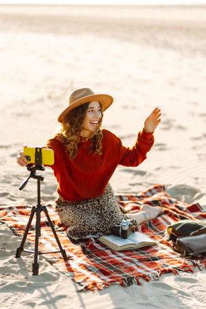 Happy woman using smartphone with stabilizer, live video in on sea beach. Live session blogging.の写真素材