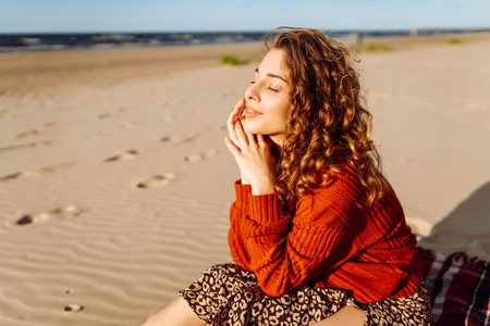 Portrait of curly woman on beach in cold sunny weather. Travel, weekend, relax and lifestyle conceptの写真素材