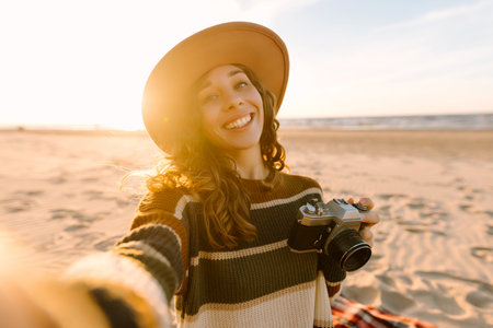 Selfie time. Young woman posing by the sea at sunset. Travel blog. Adventure, vacation concept.の写真素材