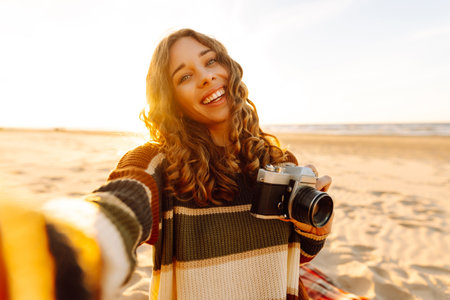 Selfie time. Young woman posing by the sea at sunset. Travel blog. Adventure, vacation concept.の写真素材