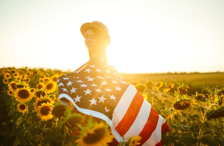 Beautiful girl in hat with the American flag in a sunflower field. 4th of July. Fourth of July. Independence Day.の写真素材