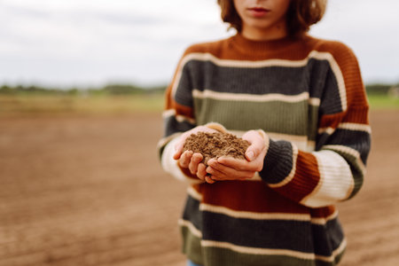 Young female farmer's hands touch dry soil in an agricultural field. Gardening and ecology concept.の写真素材
