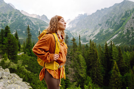 Young traveler woman with a yellow backpack on a cliff. Sports concept, traveler. Active lifestyle.の写真素材