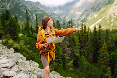 The adventure begins! Beautiful woman traveler with a yellow backpack, holds a map. Vacation conceptの写真素材