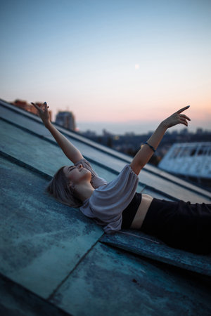 Young woman in roof enjoying sunset, freedom city atmosphere. People, lifestyle, relaxation concept.の写真素材