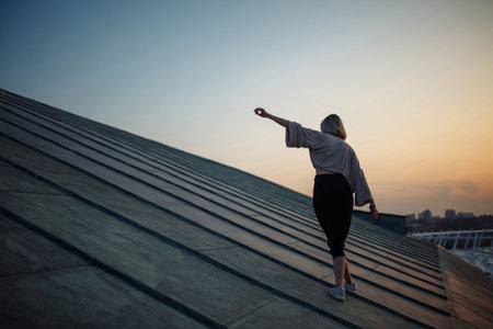 Young woman in roof enjoying sunset, freedom city atmosphere. People, lifestyle, relaxation concept.の写真素材