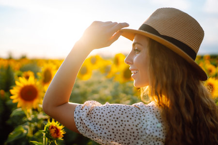 Beautiful woman posing in a field of sunflowers in a dress. Lifestyle, travel concept.の写真素材