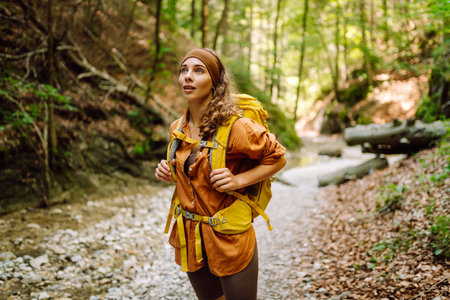 Traveler woman walking along hiking trail through forest thicket in the mountains. Active lifestyle.の写真素材