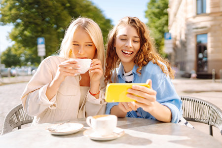 Young women enjoying in coffee and having fun with smartphone. Coffee break after shopping.の写真素材