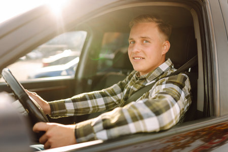 Happy man feeling comfortable sitting on driver seat in car. Lifestyle concept. Car sharing concept.の写真素材