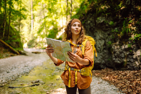 Young woman on a mountain path with a map in her hands, exploring hiking trails. Adventure concept.の写真素材