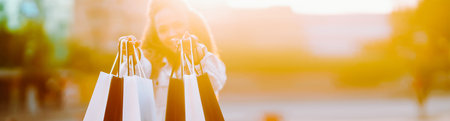 Young woman with shopping bags walking on street. Female coming from a sale downtown