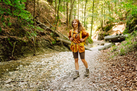Traveler woman walking along hiking trail through forest thicket in the mountains. Active lifestyle.の写真素材