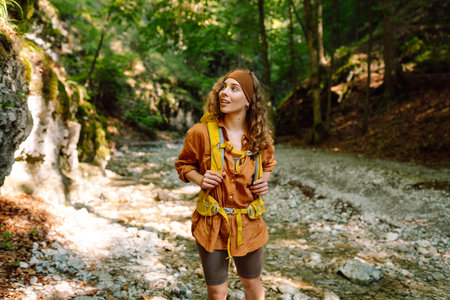 Traveler woman walking along hiking trail through forest thicket in the mountains. Active lifestyle.の写真素材