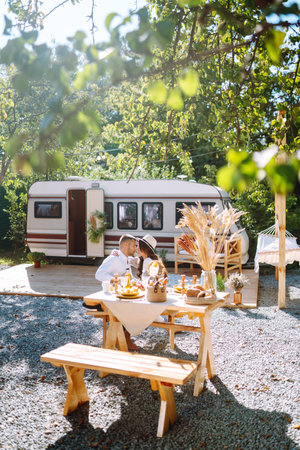 Beautiful wedding couple laugh and kiss relaxing in rv, camping in a trailer. Romantic moment.の写真素材