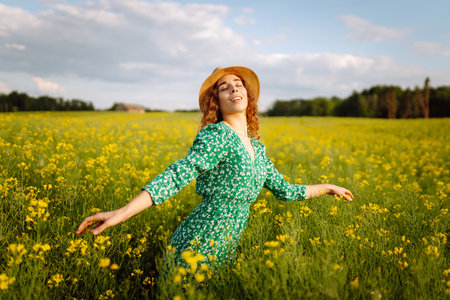 Young woman walking flowering field gently touch yellow flowers. Summer landscape.の写真素材