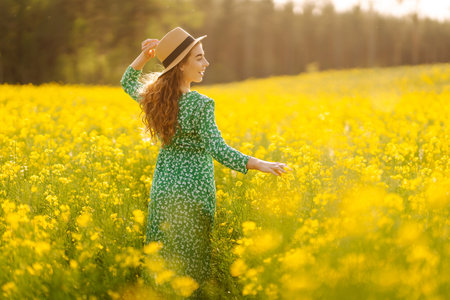 Young woman walking flowering field gently touch yellow flowers. Summer landscape.の写真素材