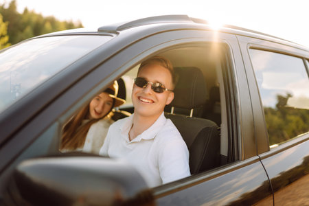 Young couple in new car is relaxing at sunset. Man has fun with girl in car at wheel Travel, tourismの写真素材
