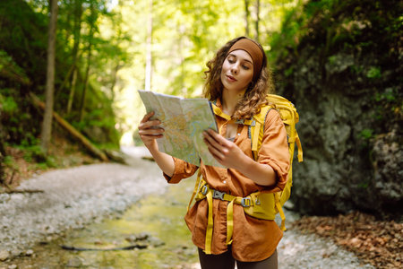 Young woman on a mountain path with a map in her hands, exploring hiking trails. Adventure concept.の写真素材