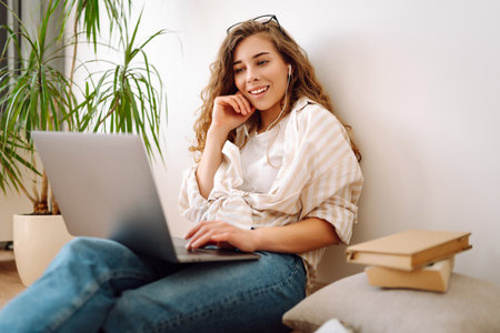 Cute woman using laptop while sitting on floor at home. Remote work from home. Freelancing concept.の写真素材
