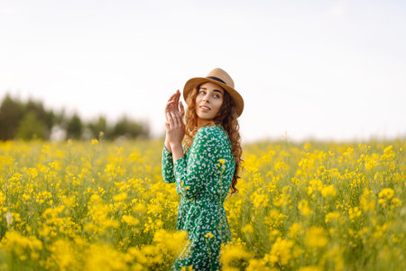 Young woman walking flowering field gently touch yellow flowers. Summer landscape.の写真素材