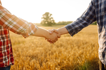 Close-up of two farmers shaking hands in a golden wheat field. Business concept, agriculture.の写真素材