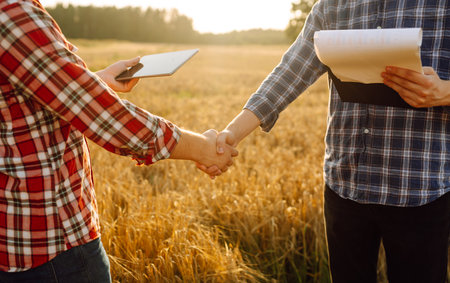 Handshake, joint work of farmers. Two farmers making agreement with handshake in wheat field.の写真素材