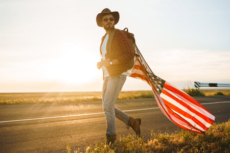 4th of July. American Flag.Patriotic holiday. Traveler with the flag of America. Beautiful sunset light. American style.の写真素材