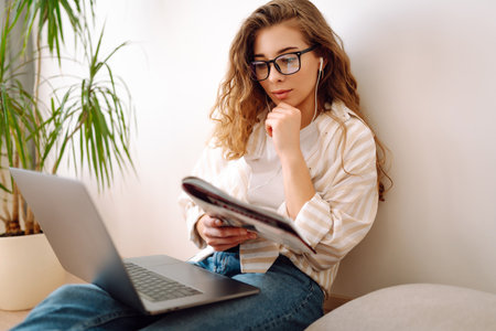 Cute woman using laptop while sitting on floor at home. Remote work from home. Freelancing concept.の写真素材