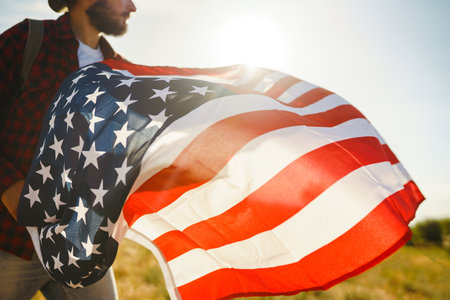 4th of July. American Flag. Traveler with the flag of America. The man in a hat, a backpack, a shirt and jeans.の写真素材