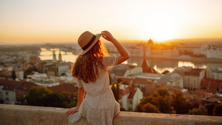 Portrait of happy woman tourist in hat at dawn enjoys cityscape. concept of an active lifestyle.の写真素材