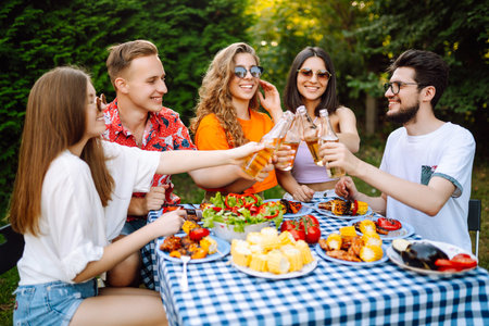 Happy friends in picnic in park. Friends grill meat, have fun, relax. ?concept of holidays, weekends.の写真素材