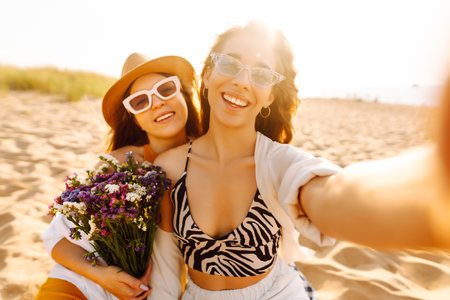 Two pretty friends women making selfie on beach, light and bright summer colors. Friends togetherの写真素材