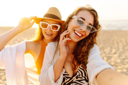 Two pretty friends women making selfie on beach, light and bright summer colors. Friends togetherの写真素材