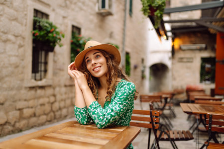 Young woman sitting by table of outdoor sidewalk cafe restaurant. People, fashion, lifestyleの写真素材