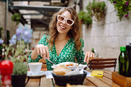 Young woman sitting in summer cafe, eating pasta with tomato, meat. Bolognese. Parmesan cheese.の写真素材