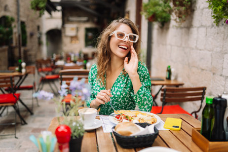Portrait of a smiling woman eating pasta at cozy Italian restaurant outdoors.の写真素材