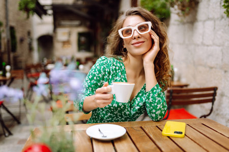 Young woman tourist drinks coffee in the old town in summer trip. People, fashion, lifestyleの写真素材