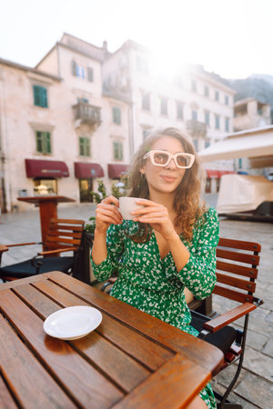Young woman enjoying coffee at a cozy outdoor cafの写真素材