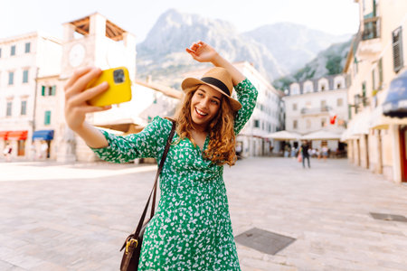 Happy woman takes a selfie photo on smartphone against the background of old city. Travel and lifeの写真素材