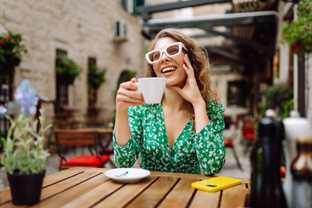 Young woman tourist drinks coffee in the old town in summer trip. People, fashion, lifestyleの写真素材
