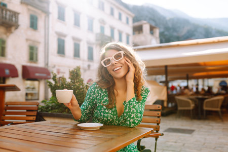 Young woman enjoying coffee at a cozy outdoor cafの写真素材