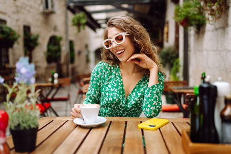 Young woman tourist drinks coffee in the old town in summer trip. People, fashion, lifestyleの写真素材