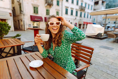 Young woman enjoying coffee at a cozy outdoor cafの写真素材