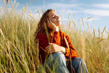 Beauty woman enjoying nature outdoors in grass. Calmness and tranquility. Travel, tourism concept.の写真素材