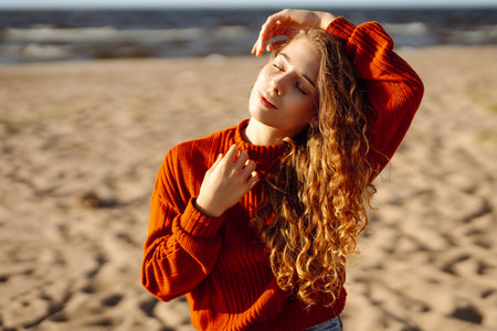 Outdoor portrait of pretty woman on the beach in cold sunny weather. Travel, fashion, bloggingの写真素材