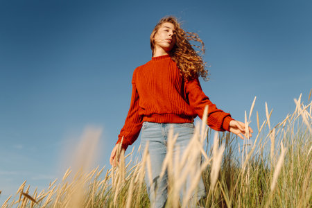 Beauty woman enjoying nature outdoors in grass. Calmness and tranquility. Travel, tourism concept.の写真素材